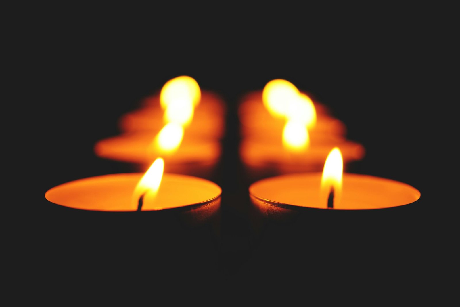 A serene row of lit candles casting warm glows in a dark setting.