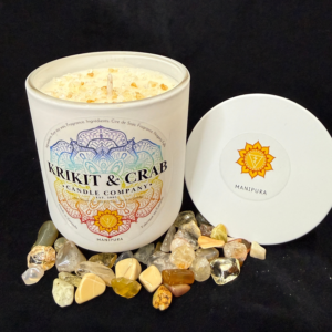 “Krikit & Crab Candle Company Manipura (Solar Plexus Chakra) candle decorated with yellow citrine chips. Surrounded by polished and raw citrine stones, with the yellow solar plexus chakra symbol on the lid.”
